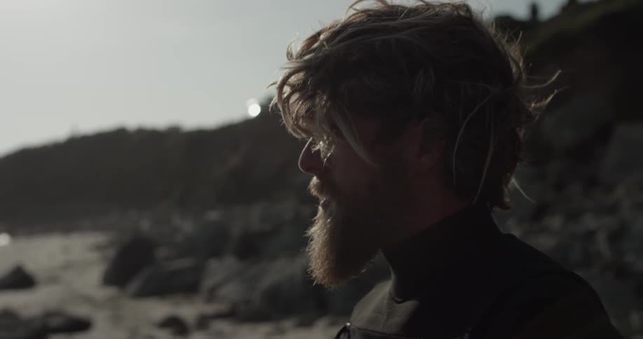 A man in a wet suit looking at the beach