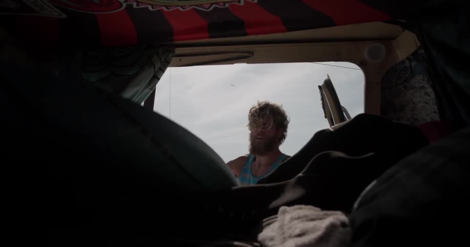 A man puts his surfing gear into the back of a vehicle