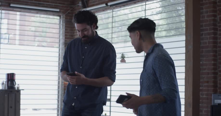 Two men talking to each other while dancing around in an office