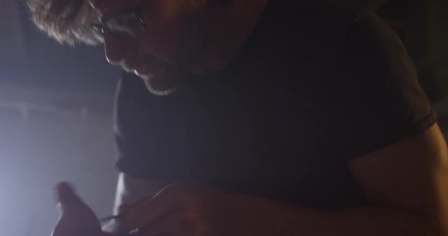 A man with glasses works on something out of sight