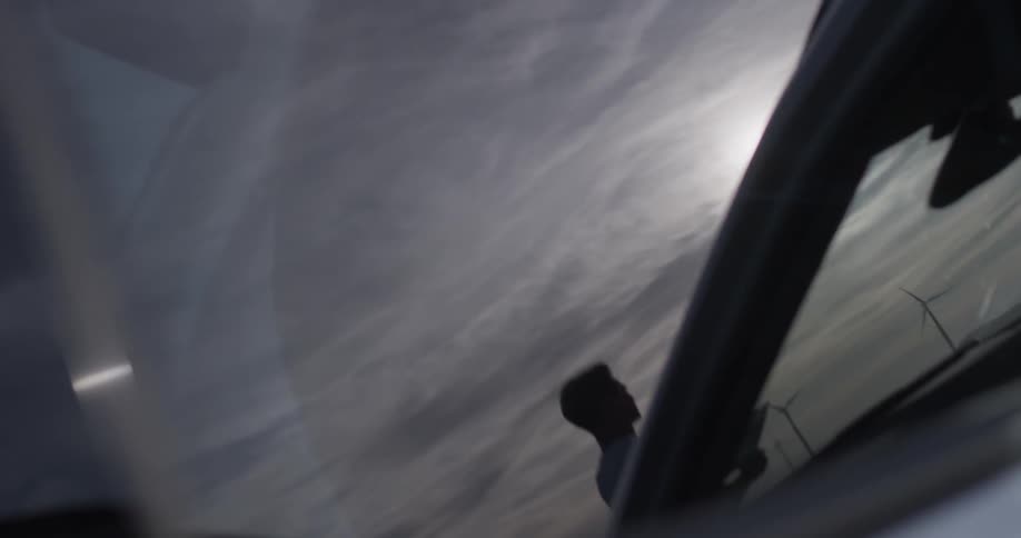 Man Driving Electric Car Through Wind Farm