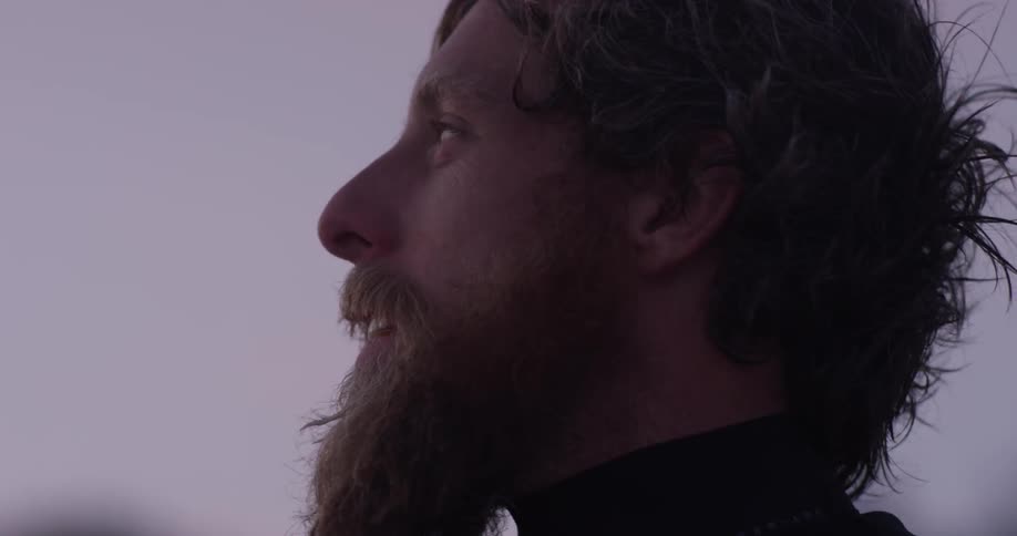 Closeup of a man with a beard exhales and looks around