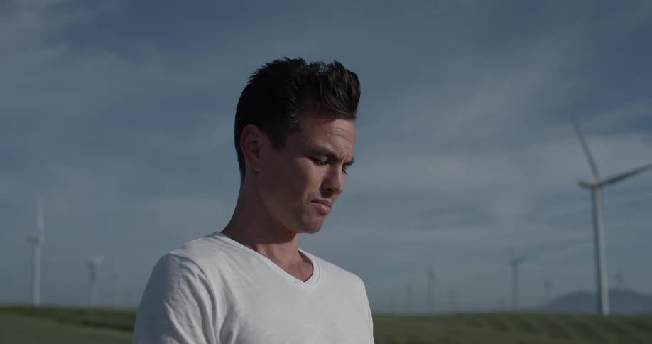 A man in a field with wind blowing his hair