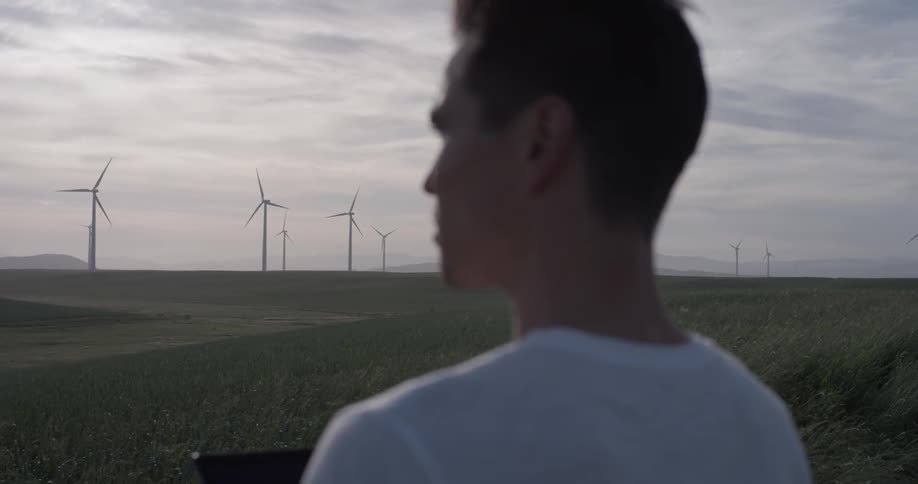 Man with tablet looks at windmills in the distance