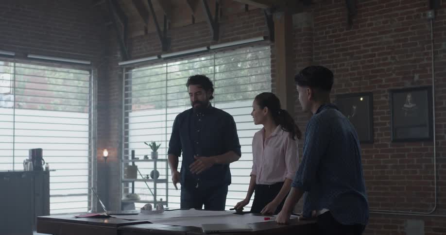 Three people discussing paperwork spread across a desk