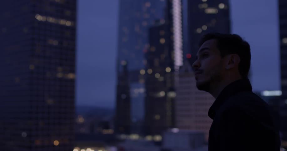 A man looks out onto the city from a rooftop