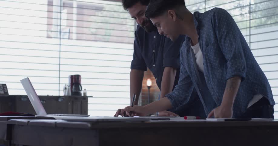 Two men that are drawing on a piece of paper in an office