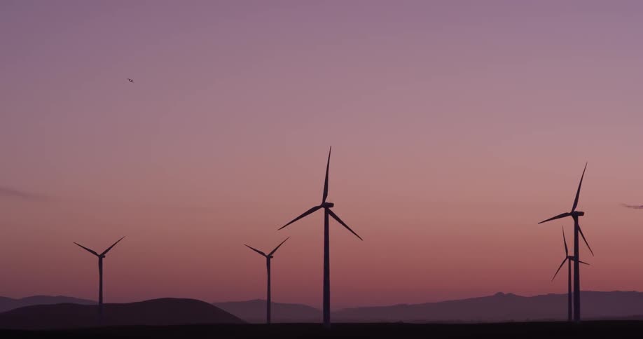 A lot of windmills rotating at sunset