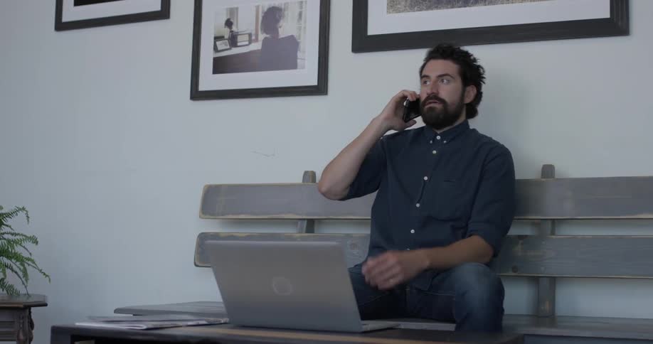 A man picking up his phone on a couch