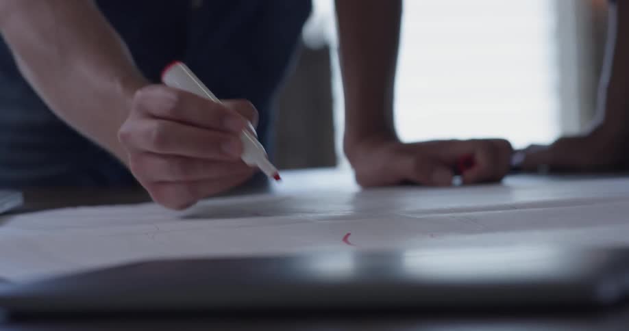 Two people write on a large piece of paper