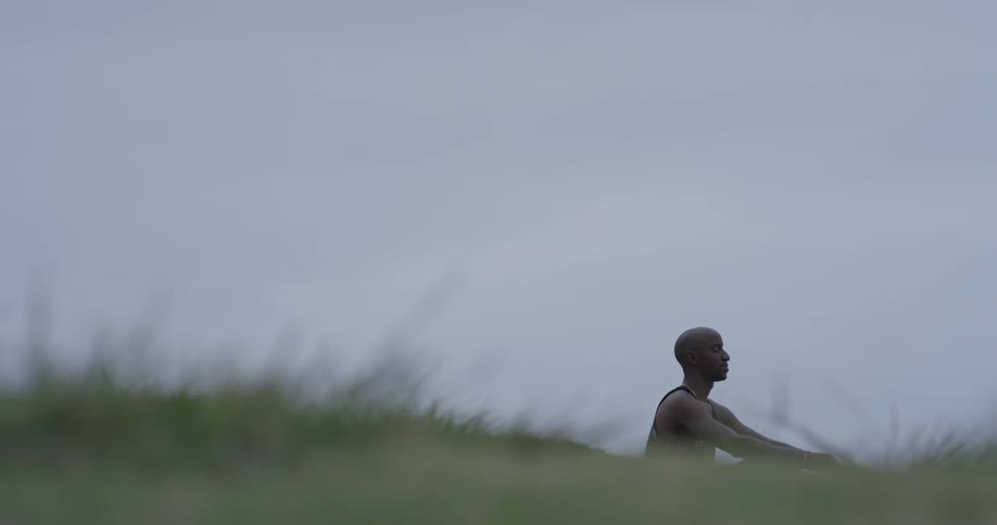 A man sitting on some grass meditating