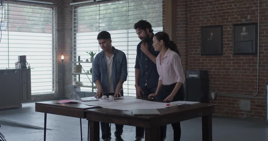 Three people looking at plans on a desk