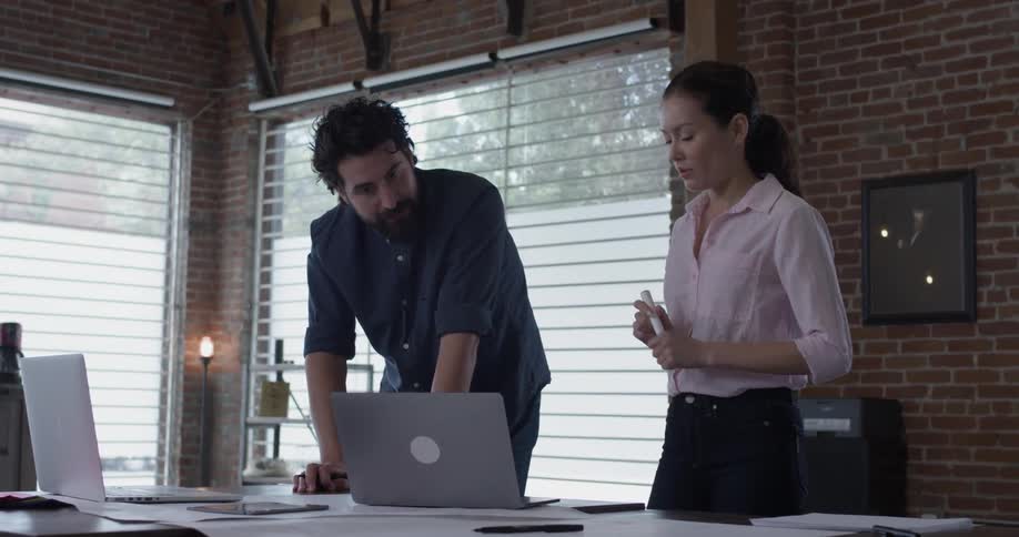 A man and woman looking at some things on a laptop