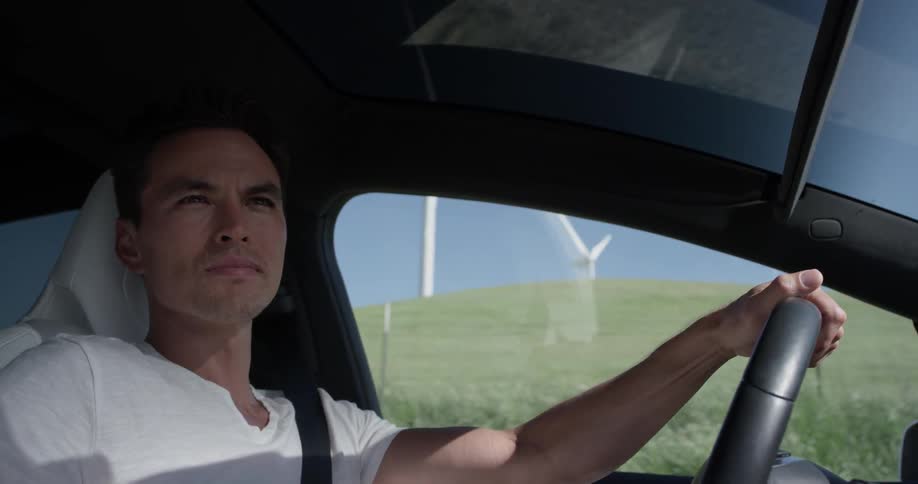 A man driving a car next to some fields