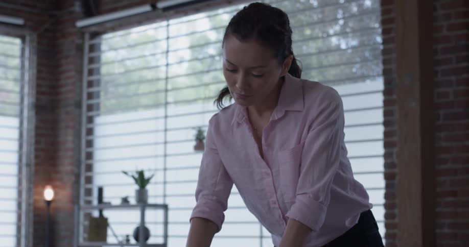 A woman is writing on paper on top of a table in the office