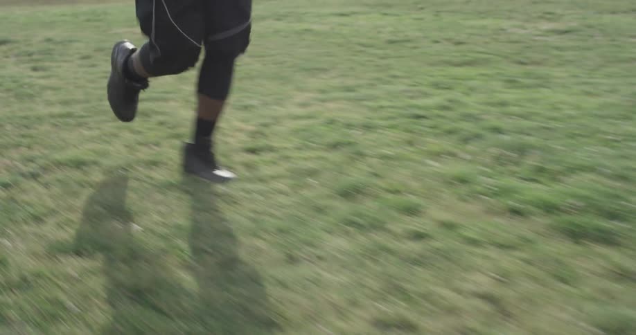 A man runs on the grass as he wears headphones