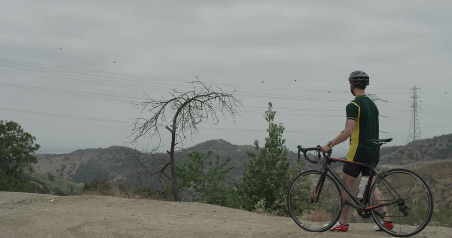 A man walks next to his bike on a cliff