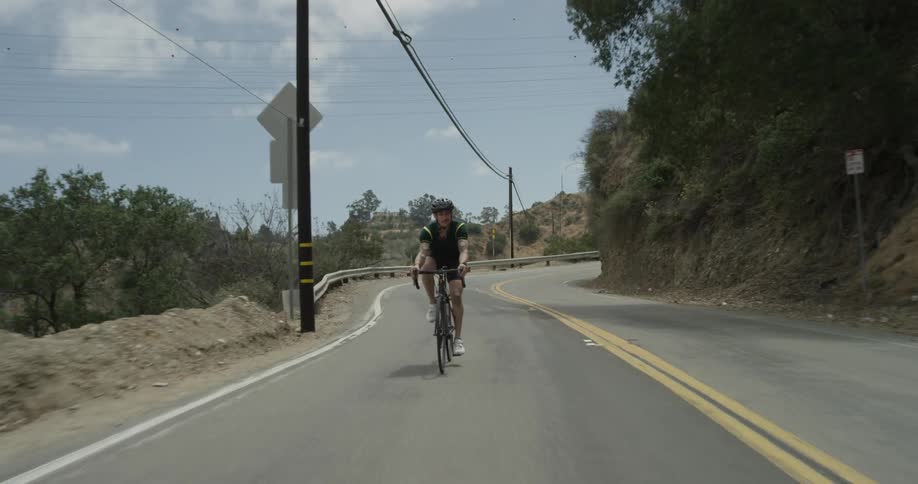 A person is riding a bicycle in the middle of the lane