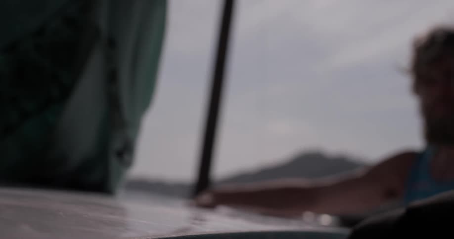 A man reaches in a vehicle to grab a surfboard