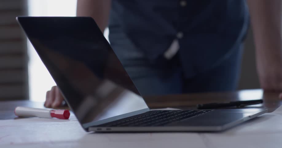 Two people discussing and gesturing over a laptop
