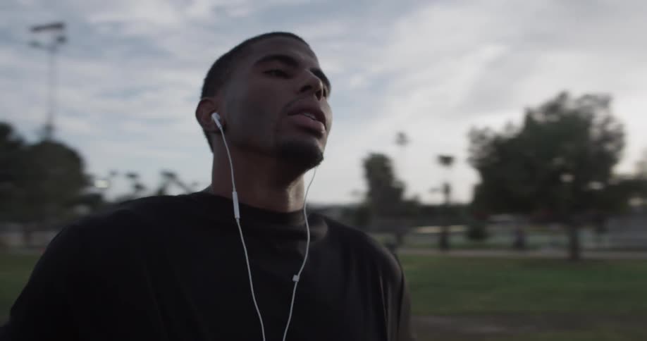 A man wearing headphones outside is resting
