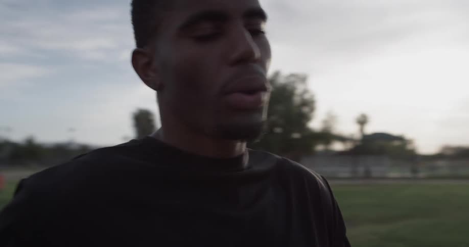 A man stands on the grass as he takes his ear buds out