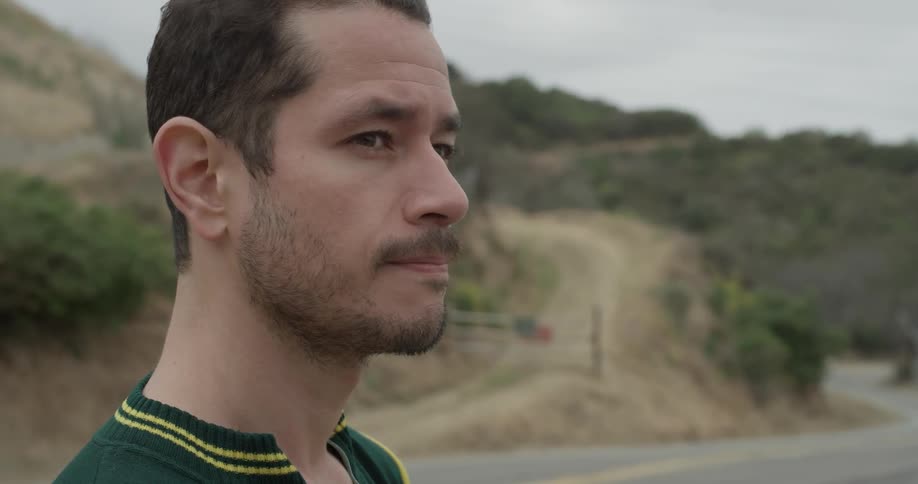 A man standing by the road looking to the distance