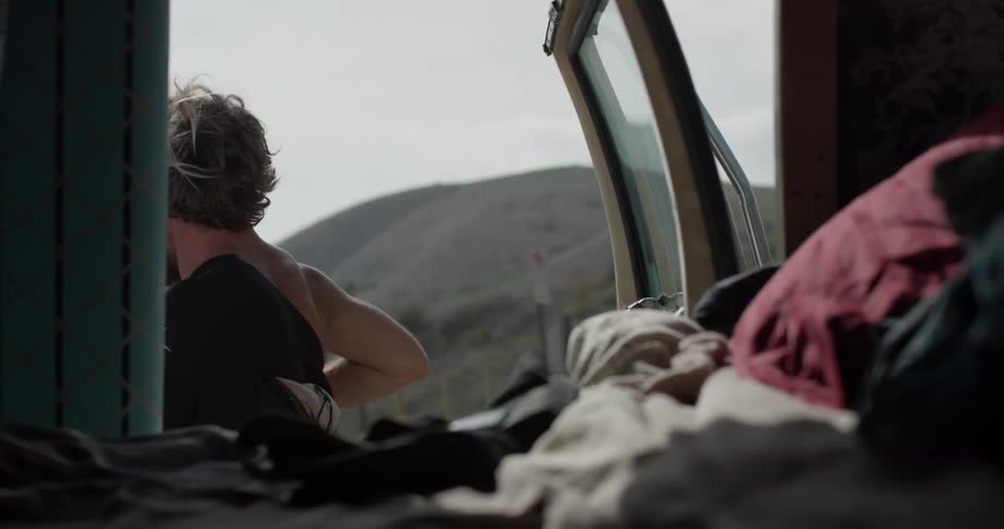 A man puts on a wetsuit behind a vehicle