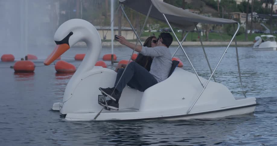A man and woman are kissing and taking pictures on the lake