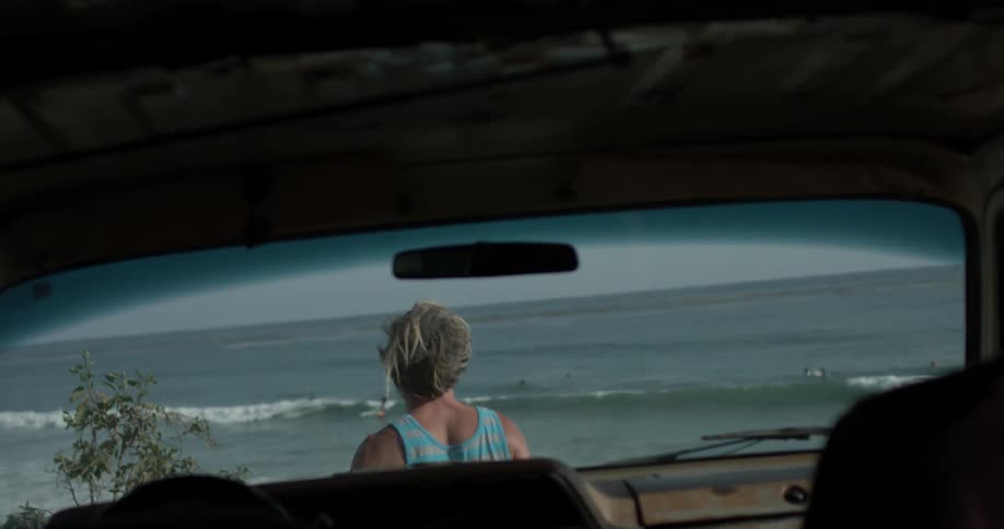 A man standing in front of a car looking at the ocean