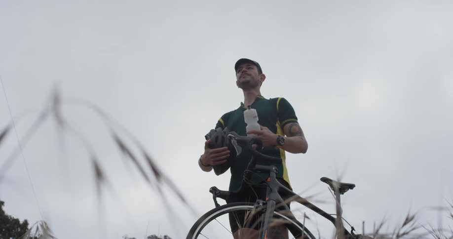 A man grabs his water bottle off his bike and drinks the water