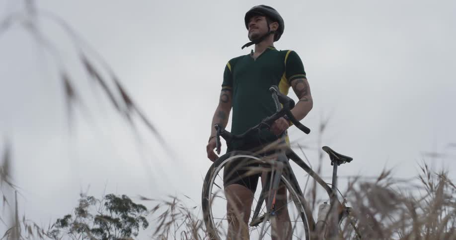 A man walking their bicycle next to a field