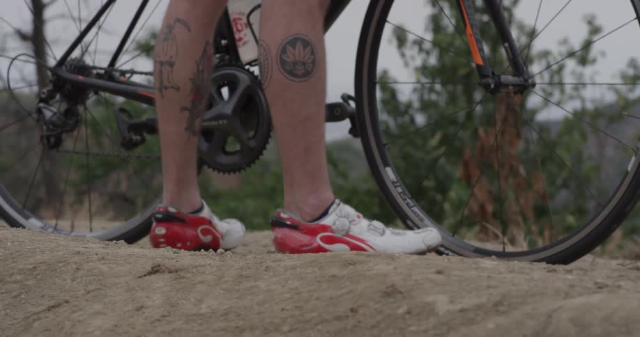 A man standing on a trail next to a bicycle