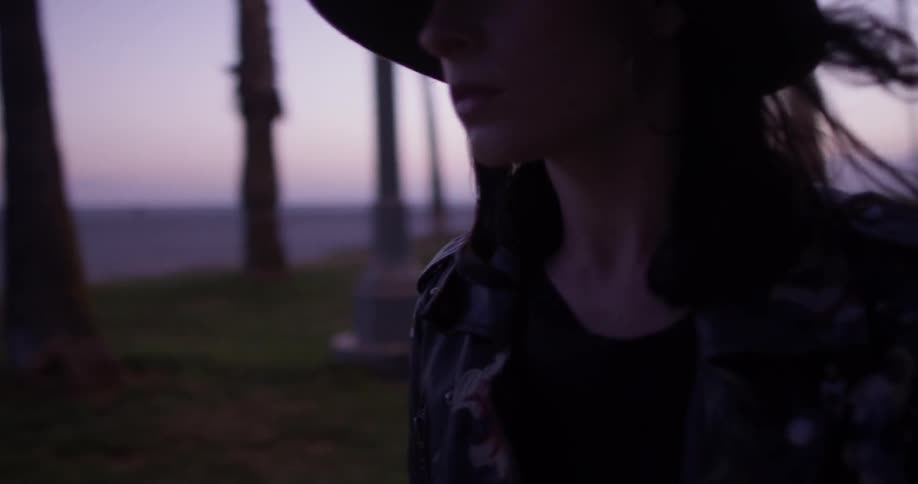A woman is walking outside wearing a hat
