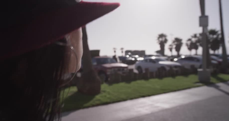 A woman is walking next to a parking lot of cars