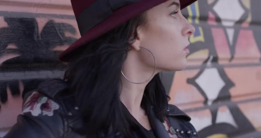 A woman strumming a guitar next to a colorful wall