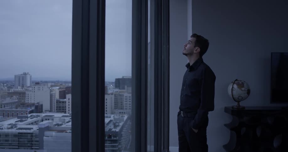 Man looking out a window with a view of the city
