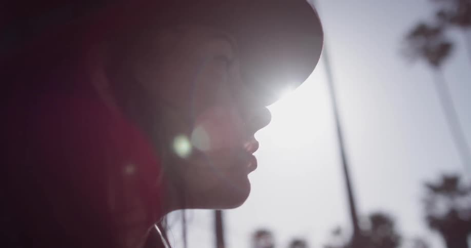 A woman in a hat standing around on a sunny day