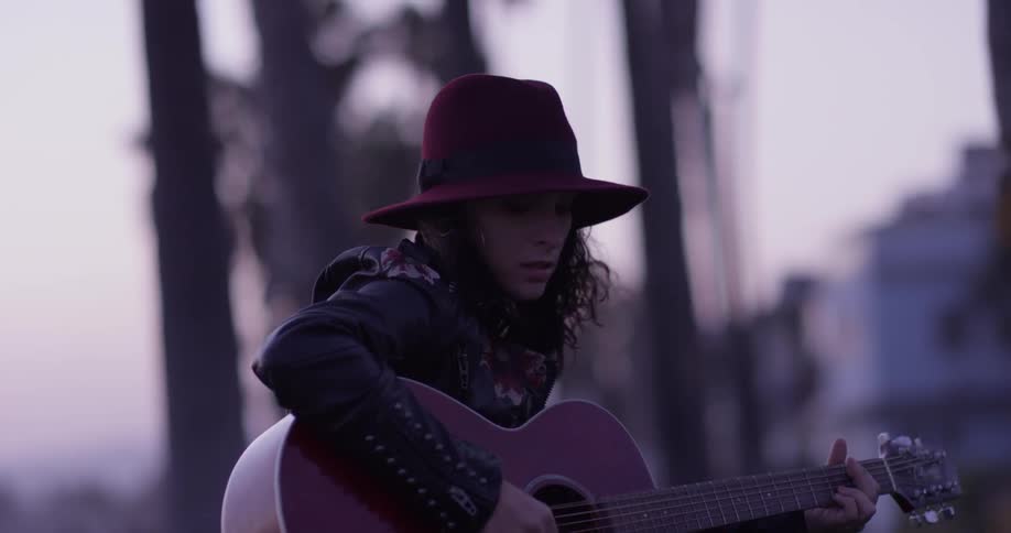 A woman sits on the grass playing a guitar