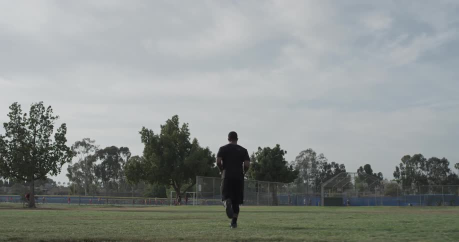 A man running down a field towards a fence