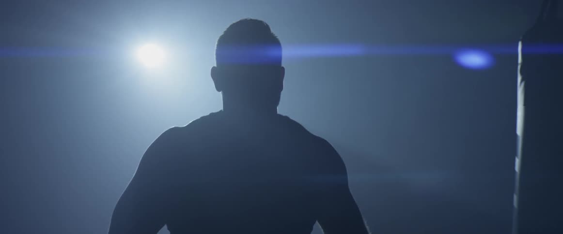 A bright light shining behind a muscular man walking