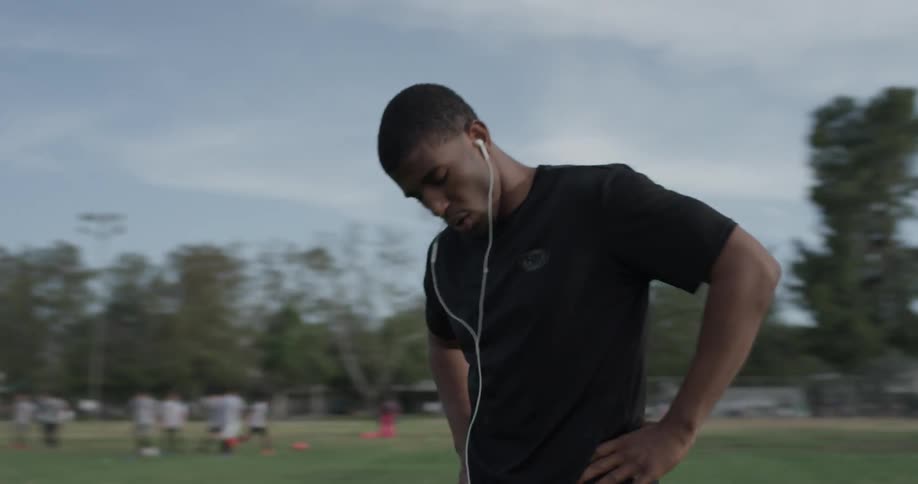 Man with earbuds psyches himself up for a workout in the park