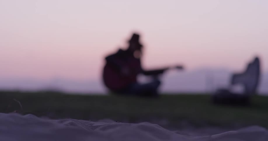 A person sitting on the grass playing a guitar