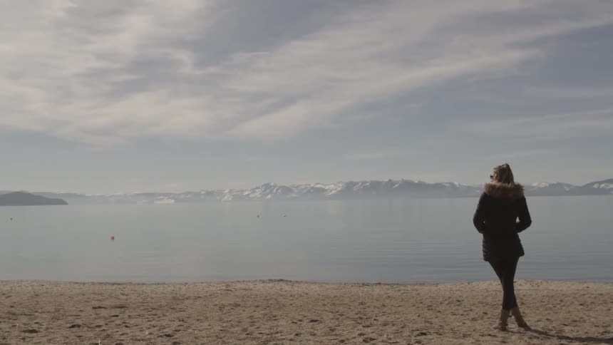 A woman standing around at the edge of a lake