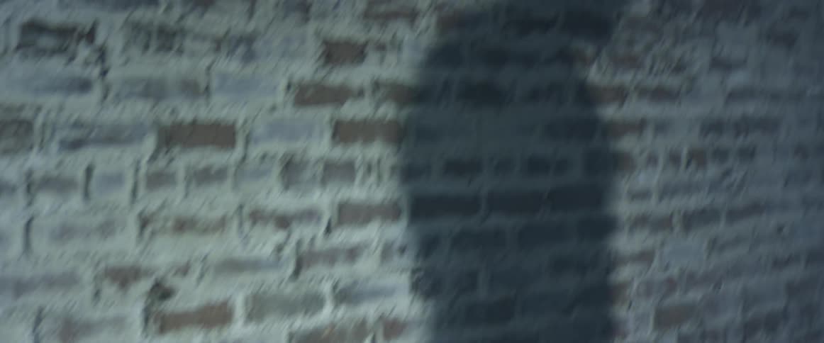 A man is walking by a brick wall