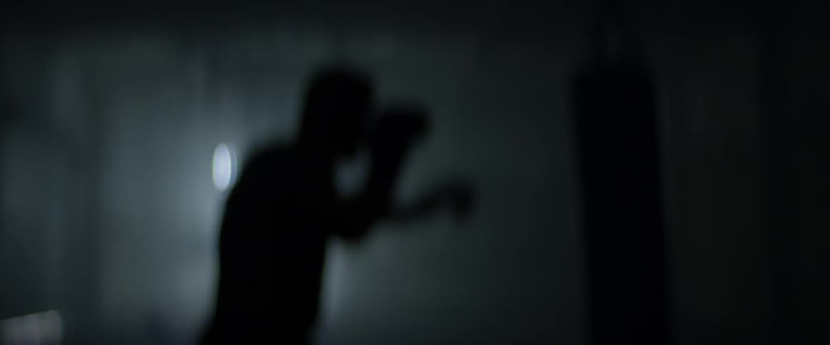 Backlit man punching a heavy bag