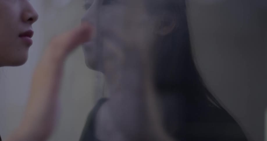 A woman running her fingers against a glass pane