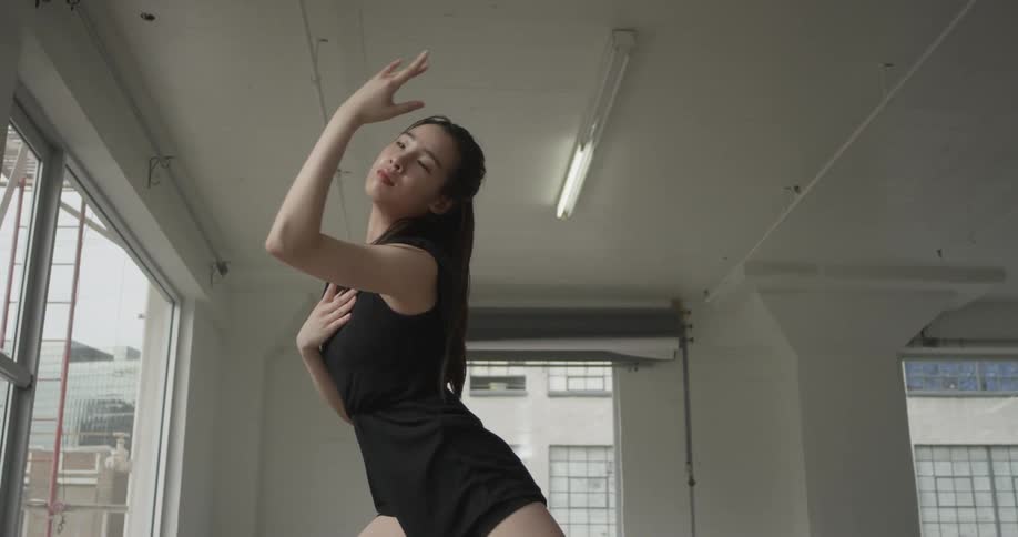 A woman in a black dress dancing in a studio