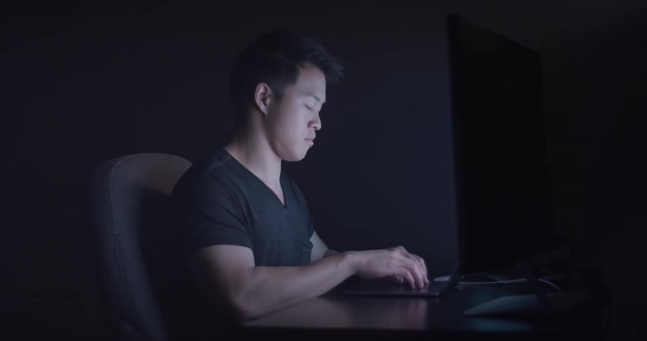A man sitting in front of a computer in an office typing