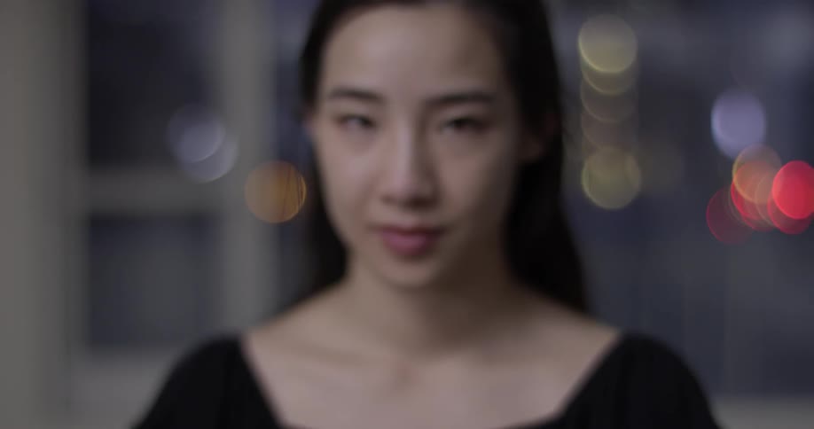 Woman in a black dress standing in a room at night